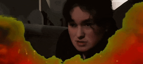 a woman in a black shirt is surrounded by a yellow and red explosion