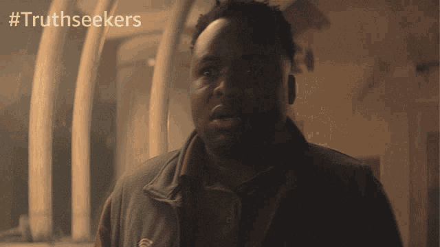 a man in a dark room with #truthseekers on the bottom