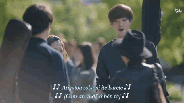 a man holding a guitar in front of a crowd of people with subtitles in a foreign language