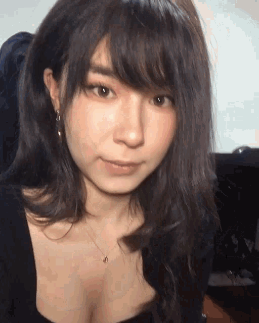 a close up of a woman 's face wearing a black top and a necklace
