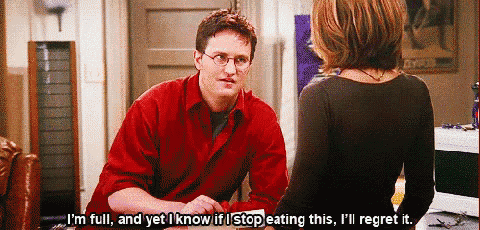 a man in a red shirt is talking to a woman in a black shirt while sitting at a table .