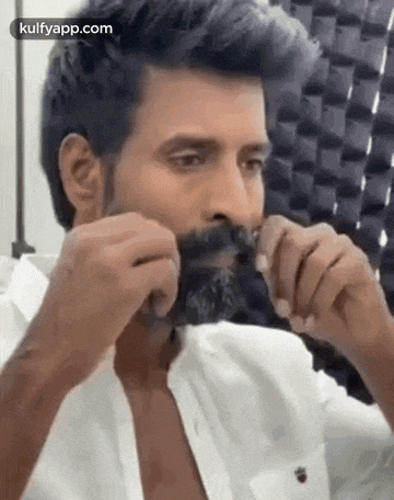 a man with a beard is brushing his mustache with a comb .