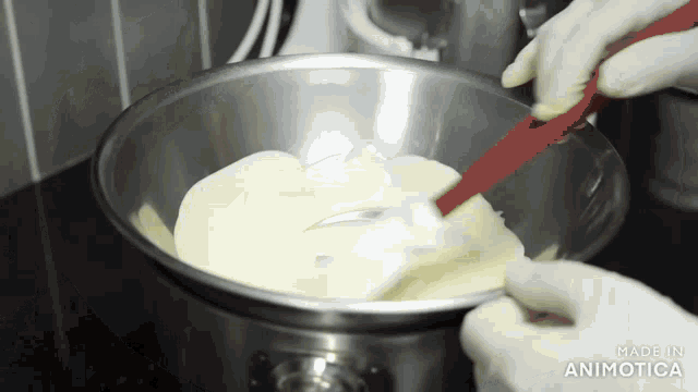 a person is mixing something in a metal bowl with a spatula and the words made in animatica visible