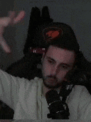 a man is sitting in front of a microphone and making a funny face .