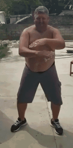 a shirtless man in shorts and sneakers is standing on a sidewalk with his arms outstretched .