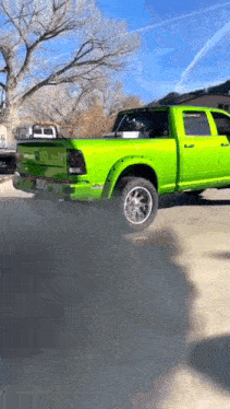 a bright green pickup truck is parked in a driveway .