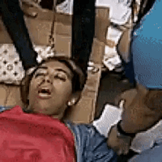 a woman in a red shirt is laying on the ground with her eyes closed .