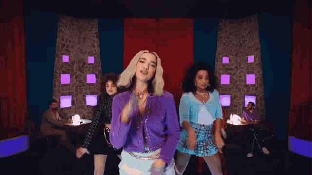 a woman in a purple jacket is dancing with a group of other women