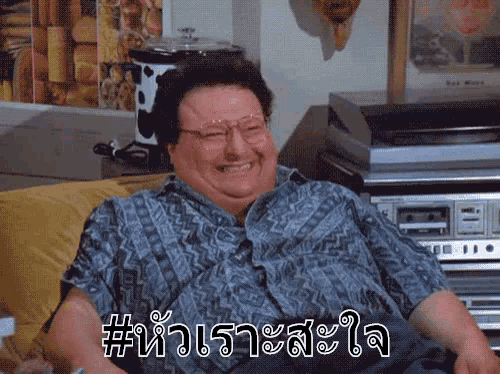 a man is sitting on a couch laughing in a room with foreign writing