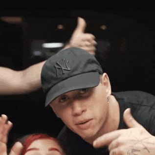a man wearing a new york yankees hat giving a thumbs up