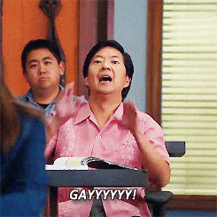 a man in a pink shirt is sitting at a desk and says gayyyyy