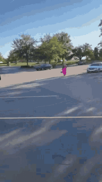a woman in a pink dress is walking down a street