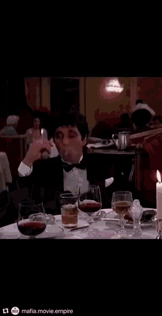 a man is smoking a cigar while sitting at a table in a bar .
