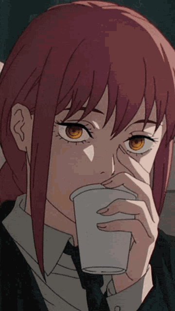 a girl with red hair drinking from a cup