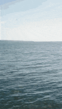 a large body of water with waves and a blue sky