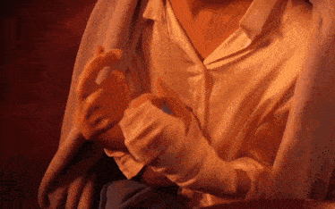 a woman wearing a white shirt and white gloves is sitting under a blanket .