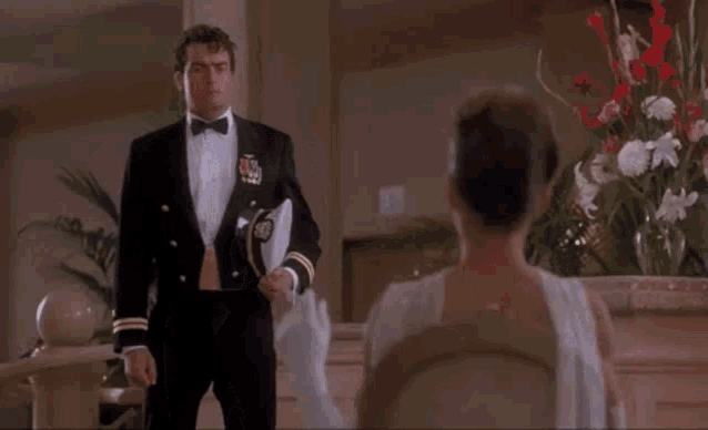 a man in a tuxedo is standing in front of a woman in a white dress .