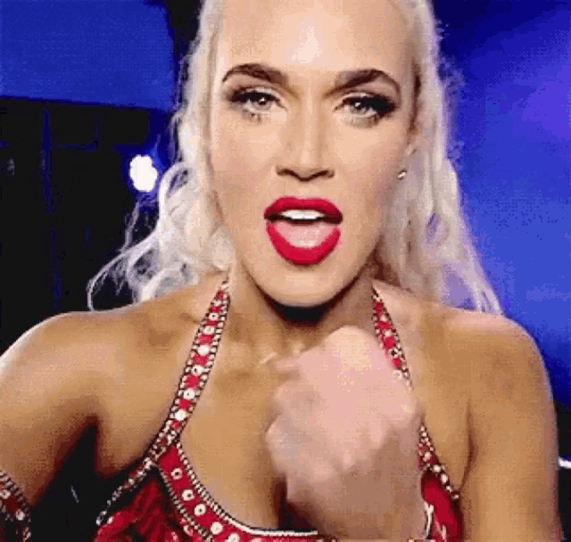 a woman in a red dress with red lipstick is making a fist gesture .