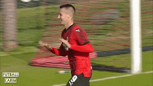 a soccer player wearing a red jersey that says emirates on it