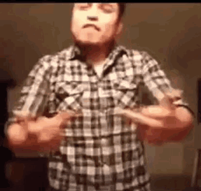 a man in a plaid shirt is making a funny face while dancing .