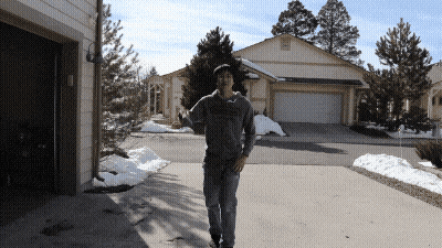 a man is walking down a driveway in front of a garage door
