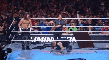 a wrestler is kneeling down in front of a sign that says ' luminaria ' on it