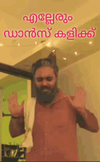 a man with a beard is dancing in front of a sign that says ' malayalam '
