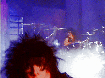 a blurred image of a person playing a drum set in a dark room