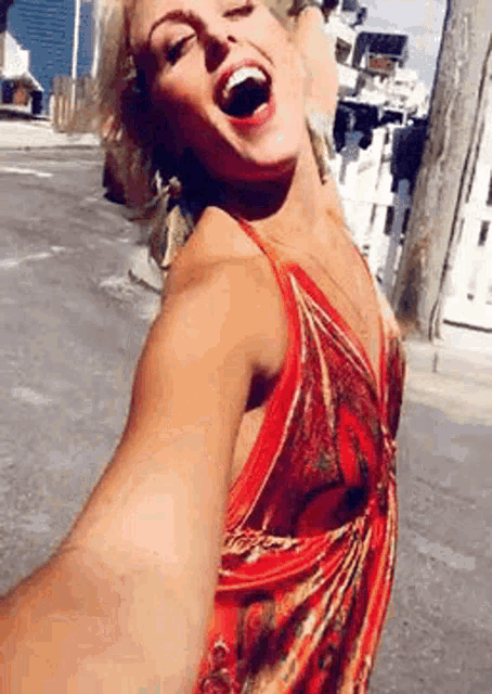 a woman in a red dress is taking a selfie on a street .