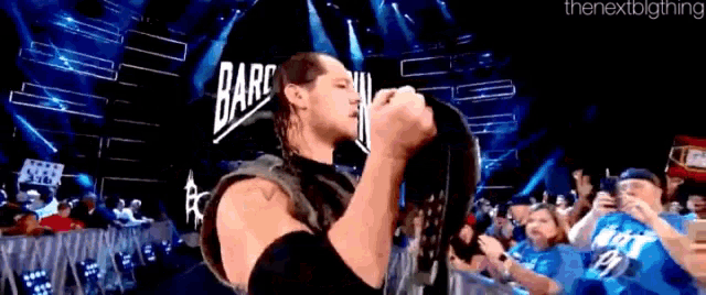 a wrestler is kissing his hat in front of a crowd of people .