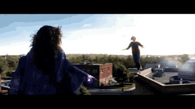 a woman in a purple cape is standing on a ledge with a man in a red shirt behind her
