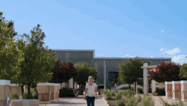a woman walking down a sidewalk in front of a large building