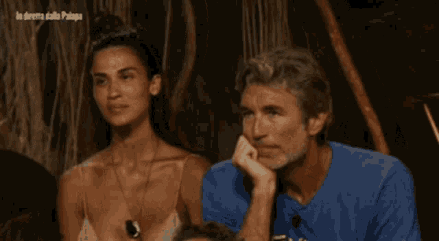 a man in a blue t-shirt with the word tivoli on it sits next to a woman