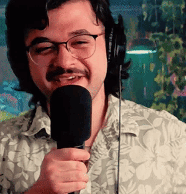 a man with glasses and a mustache is holding a microphone and smiling