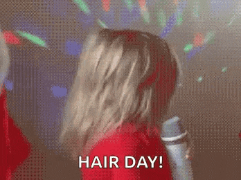 a woman in a red shirt is holding a spray bottle and saying `` hair day ! ''