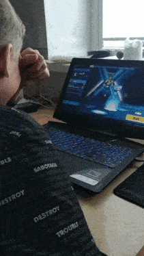 a man sitting in front of a laptop with the word destroy on his back