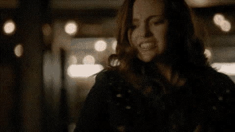 a woman in a black jacket is standing in a dark room .