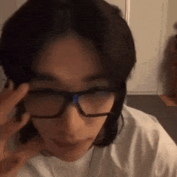a close up of a person wearing glasses with their hand on their face .