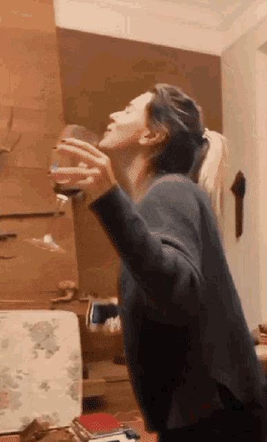 a woman is drinking a glass of wine in a room