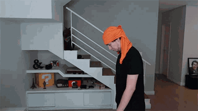 a man wearing an orange head scarf walking down stairs