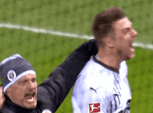 a soccer player wearing a puma jersey is being hugged by another man
