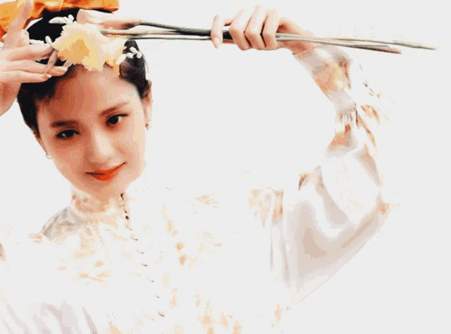 a woman with a bun on her head is holding a flower in front of her eye