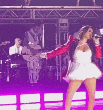 a woman singing into a microphone with a band behind her