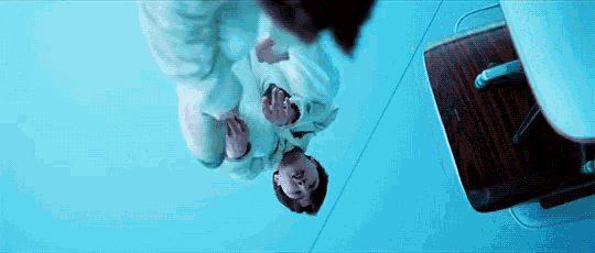 a person is standing upside down in a blue room with a chair .