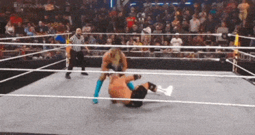 a wrestling match is taking place in a ring with a referee watching .
