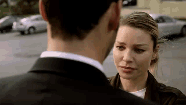 a man and a woman are standing next to each other in a parking lot .