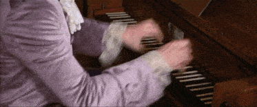 a person in a purple shirt is playing a keyboard