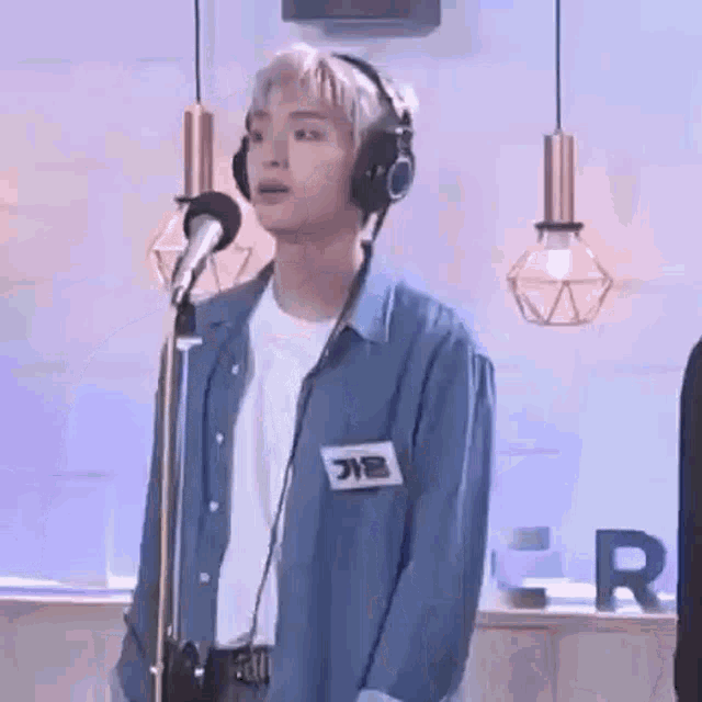 a young man wearing headphones is singing into a microphone in a recording studio .