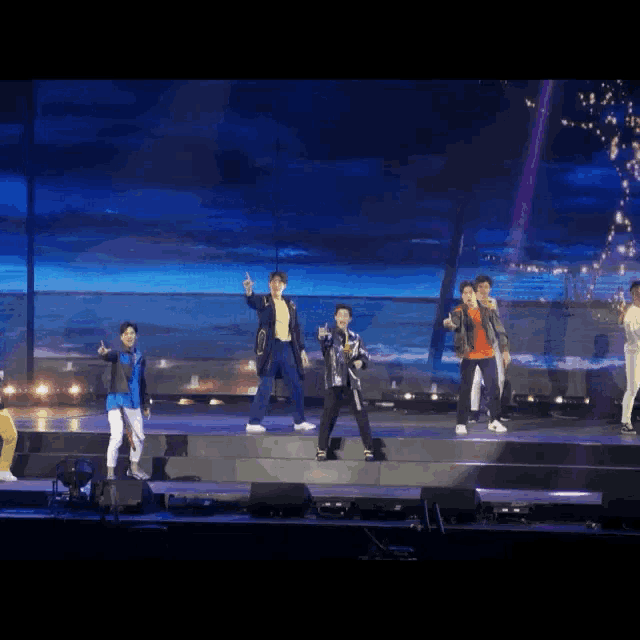 a group of young men are standing on a stage giving the thumbs up sign