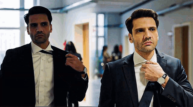 two men in suits and ties are standing next to each other